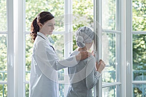 Doctor in white uniform supporting sick girl with headscarf
