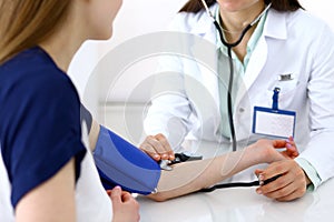 Doctor woman checking blood pressure of female patient, close-up. Cardiology in medicine and health care concept