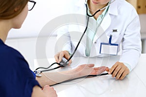 Doctor woman checking blood pressure of female patient, close-up. Cardiology in medicine and health care concept