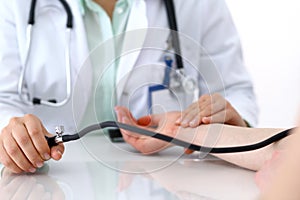 Doctor woman checking blood pressure of female patient, close-up. Cardiology in medicine and health care concept