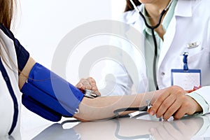 Doctor woman checking blood pressure of female patient, close-up. Cardiology in medicine and health care concept