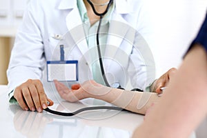 Doctor woman checking blood pressure of female patient, close-up. Cardiology in medicine and health care concept