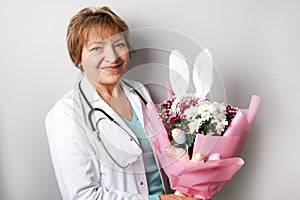 Doctor woman with easter spring bouquet of flowers, colorful eggs and bunny ears