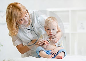 Doctor woman examining heartbeat of kid boy with