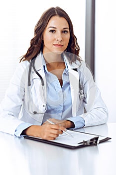 Doctor woman filling up medical form while sitting at the desk in hospital office. Physician at work. Medicine and