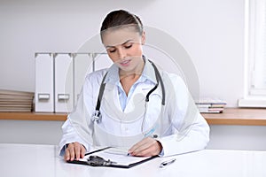 Lékař žena náplň nahoru zdravotní formulář zatímco na psací stůl. a péče 