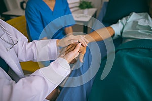 Doctor woman holding hand for reassuring her senior man patient.