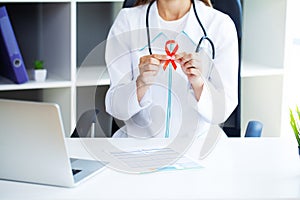 Doctor woman holding a red ribbon emerges from a critical situation after overcoming AIDS