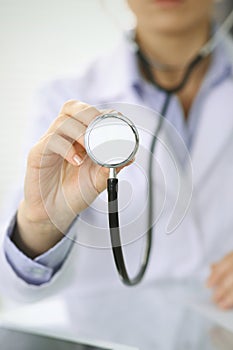 Doctor woman holds stethoscope head, close-up of hands. Physician ready to examine and help patient. Helping and