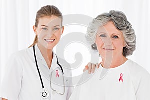 Doctor woman and patient with breast cancer awareness ribbons