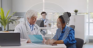 Doctor and woman patient discussing treatment or medical record data at modern diagnostic center