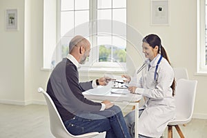 Doctor woman and patient are sitting at a table in the office of a medical clinic.