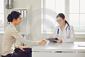 Doctor woman pediatrician gynecologist talking client sitting at a table in a clinic office.