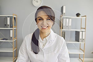 Doctor woman.Positive smiling woman doctor therapist looking at the camera while sitting at a table in a clinic office.