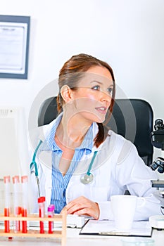 Doctor woman sitting at table and looking away