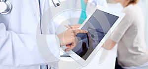Doctor woman using tablet computer, close-up of hands at touch pad screen. Medicine concept