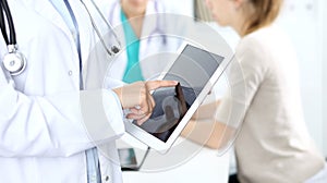 Doctor woman using tablet computer, close-up of hands at touch pad screen. Medicine and data concepts