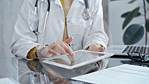 Doctor woman using tablet on the glass desk in medical office. Medicine and health care