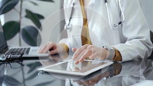 Doctor woman using using tablet on the glass desk in medical office. Medicine and health care