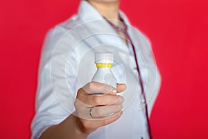 Doctor woman in white coat holding a bottle with medicine