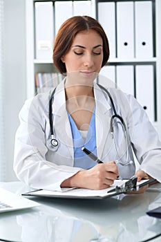 Doctor woman at work. Physician filling up medical history records form at the desk. Medicine, healthcare concept