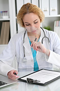 Doctor woman at work. Physician filling up medical history records form at the desk. Medicine, healthcare concept