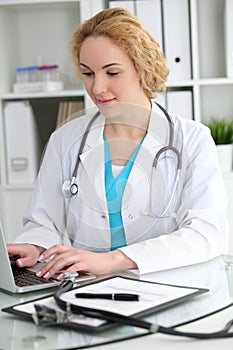 Doctor woman at work. Physician typing on laptop computer. Medicine, healthcare concept