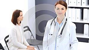 Doctor woman at work. Portrait of female physician cheerful smiling while standing near reception desk at clinic or