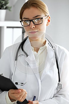 Doctor woman at work. Portrait of female physician using clipboard at hospital office. Medicine and healthcare concept
