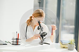 Doctor woman working a microscope. Female scientist looking through a microscope in lab. Student looking in a microscope
