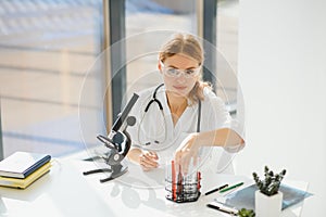 Doctor woman working a microscope. Female scientist looking through a microscope in lab. Student looking in a microscope