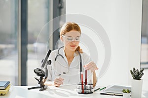 Doctor woman working a microscope. Female scientist looking through a microscope in lab. Student looking in a microscope