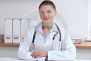 Doctor woman writing papers at the desk in hospital office. Medicine and over work concept