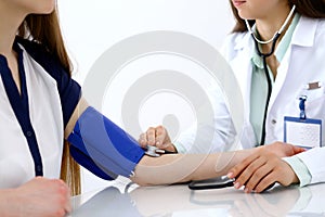 Doctor woman checking blood pressure of female patient, close-up. Cardiology in medicine and health care concept photo