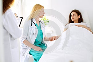 Doctor woman or nurse in a hospital office with her colleague and patient in the background. Healthcare and medicine