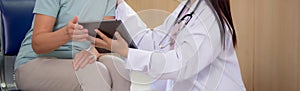 Doctor woman and senior patient talking and looking on tablet computer for diagnostics and examining disease at hospital.