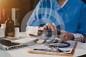 Doctor working on desk with laptop computer and paperwork in the office.