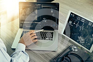 Doctor working with digital tablet and laptop computer with smart phone in medical workspace office and video conferance as