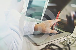 Doctor working with digital tablet and laptop computer with smart phone in medical workspace office and video conferance as