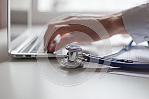 Doctor working with laptop computer in medical workspace office. Focus on stethoscope