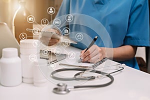 Doctor working on laptop computer and tablet and medical stethoscope on clipboard on desk.