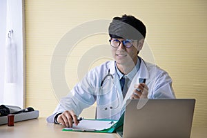 Doctor working with laptop computer  and writing on paperwork