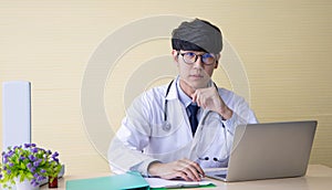 Doctor working with laptop computer  and writing on paperwork