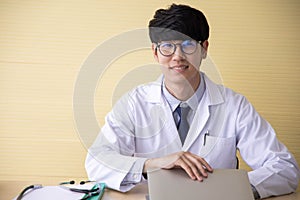 Doctor working with laptop computer and writing on paperwork