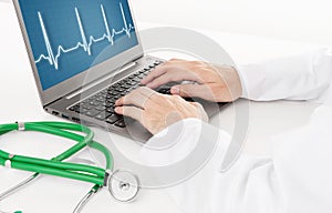 Doctor working on laptop with heart rhythm ekg on screen