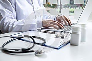 Doctor working with laptop in hospital and medical stethoscope, medicine on clipboard on desk