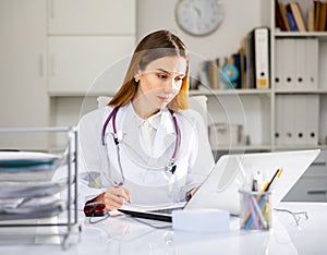 Doctor working at laptop in medical office