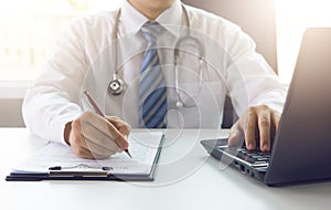 Doctor working with medical statistics and financial reports in office