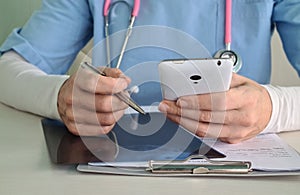 Doctor working at office desk using smartphone 911 and 112