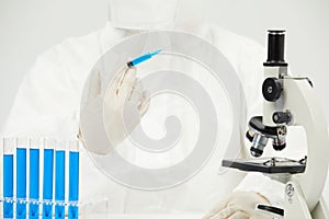 Doctor working with an optical microscope in a medical laboratory with test tubes on the table
